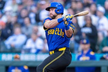 Cal Raleigh wearing a retro jersey finishing a swing