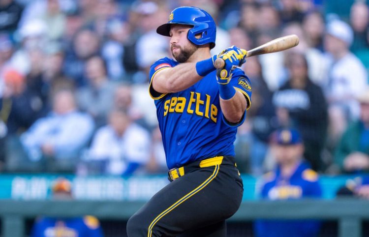 Cal Raleigh wearing a retro jersey finishing a swing