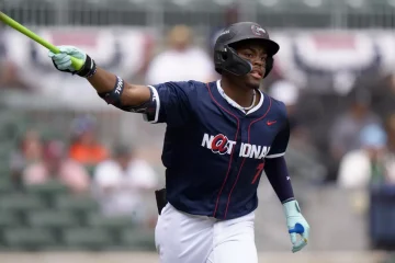 Josue De Paula finishing his swing, holding bat in one hand